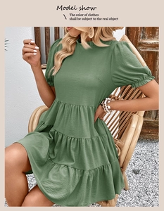 Detailed view of the layered ruffle hem and textured fabric on bean green babydoll dress