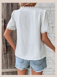 Close-up of Swiss dot fabric and floral lace stitching on back of white summer blouse
