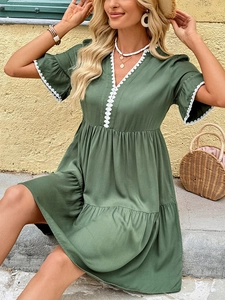 Detail of V-neckline with white lace trim on a dark green summer A-line dress