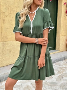 Detail of dark green dress with V-neck lace trim and ruffled short sleeves