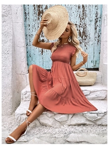 Détail d'une robe d'été corail avec taille élastique froncée et ourlet à plusieurs niveaux