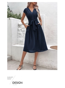 Detail of navy blue V-neck dress showing waist tie bow and functional side pockets