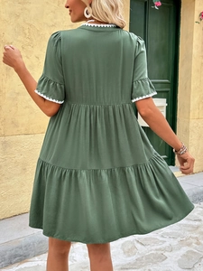 Detail of dark green tiered summer dress with white lace trim on sleeves and V-neck