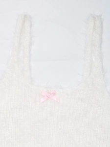 Dettaglio di canotta in maglia bianca pelosa con un delicato fiocco di seta rosa