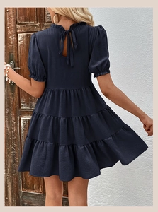 Detail of the back view of a navy blue tiered mini dress with elegant bow-tie fastening