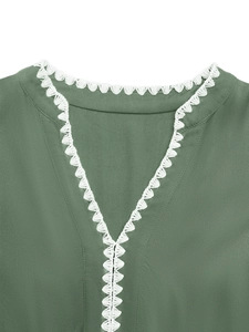 Detailed macro view of the V-neckline with white lace trim on olive green fabric