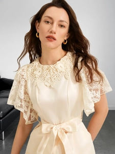 Detail of delicate beige lace embroidery and silk-textured fabric on this jumpsuit