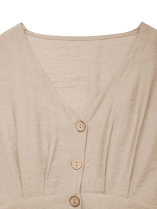 Detailed V-neckline of a beige linen jumpsuit featuring three rustic wood texture buttons
