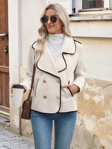 Detail of the double-breasted white coat with black trim in an elegant outdoor street setting