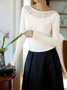 Detail of elegant mesh patchwork neckline with 3D petals and pearls on cream blouse