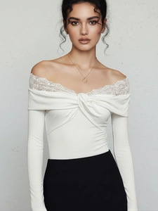 Detail of elegant white off-shoulder bodysuit with lace trim and twisted knot front design