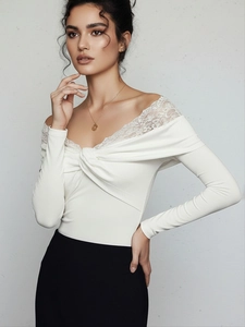 Detail of white off-the-shoulder bodysuit with delicate lace trim and twist knot front