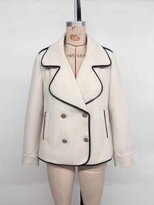 Detailed view of ivory short coat with black contrast piping and gold metal buttons