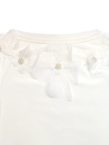 Detailed close-up of white mesh flower collar with pearl bead on knit top