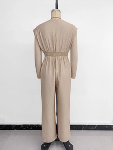 Detail of the high-waisted elastic pleats and beige textured fabric on a jumpsuit
