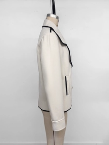 Detail of cream cropped wool jacket with black contrast trim and large notched lapel