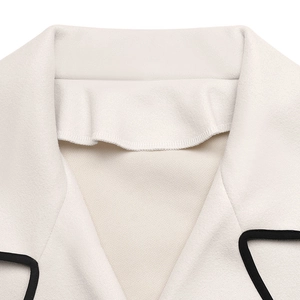 Detail of elegant cream wool coat featuring a notched lapel and contrast black piping trim