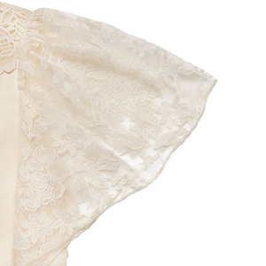 Close-up of delicate floral lace sleeves and scalloped neckline on a cream jumpsuit