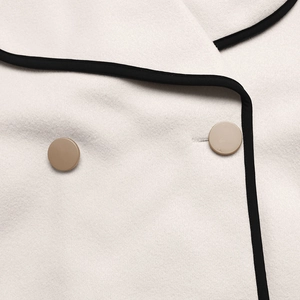 Detailed macro view of beige wool coat featuring black piping and brown matte buttons