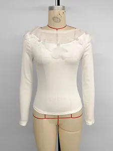 Detail of white slim-fit top featuring organza flower appliques and pearl centers