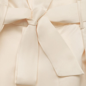 Close-up of cream satin jumpsuit waist with an elegant ribbon bow tie detail