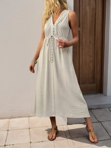 Detail of V-neck pleated dress with button accents and breathable linen-like texture
