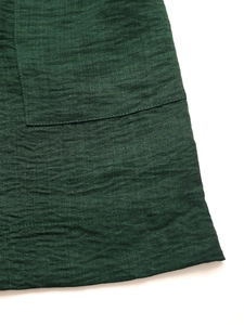 Detail of dark green textured fabric with fine horizontal pleats and neat stitching