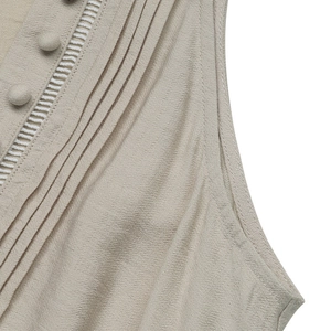 Detail of V-neck dress featuring fabric buttons, pleated texture, and white eyelet lace trim