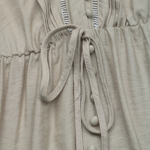 Detailed view of the champagne dress waist featuring fabric buttons and ladder stitch lace