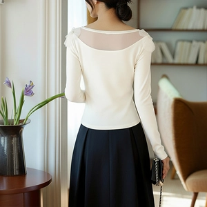 Elegant white long sleeve top with mesh back and pearl accents on black pleated skirt