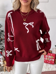 Close-up of dark red Christmas sweater featuring white bow jacquard and ribbed knit texture