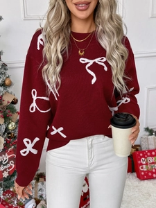 Macro detail of wine red knit sweater with white bow jacquard and ribbed crew neckline