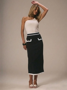 Detail of high-waisted midi skirt featuring contrast trim and metal button pockets