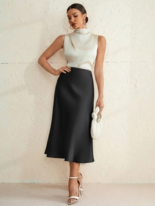 Elegant woman in cream satin sleeveless top and high-waist black midi mermaid skirt