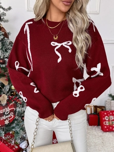 Detail of red Christmas sweater featuring white bow jacquard patterns and ribbed round neck