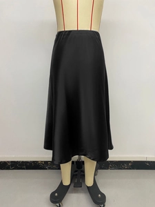 Detail view of smooth black satin midi skirt with elegant flow on a tailor mannequin