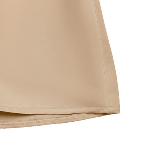Détail macro de la texture satinée beige lisse et des coutures de l'ourlet de la robe