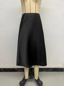 Detail of black satin high-waisted midi skirt with smooth texture and fishtail hem