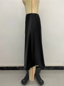 Detail of black satin high-waisted midi skirt with a silky glossy texture on a mannequin