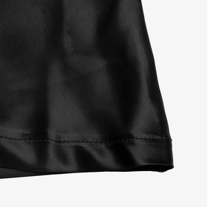 Detail of black satin skirt hem showing smooth silk texture and fine stitching work