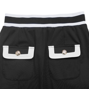 Detail of elastic black and white striped waistband and pockets with gold embossed buttons