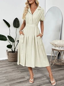 Detail of light green short-sleeved shirt dress with lapel collar and pleated skirt