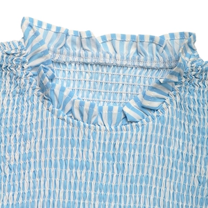 Close-up of blue and white striped fabric with smocking detail and ruffle neckline
