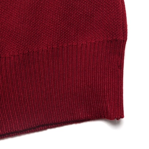 Detail of red knitted sweater hem showing premium wide ribbed texture and stitching
