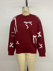 Detail view of the burgundy knit sweater showing white bow patterns and ribbed cuffs