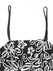 Gros plan du haut en tricot noir avec broderie florale blanche et fines bretelles