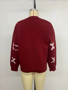 Detailed back view of burgundy knitted sweater with white bow patterns on long sleeves