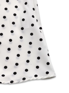 Gros plan détaillé du tissu blanc à pois noirs avec couture de finition du vêtement