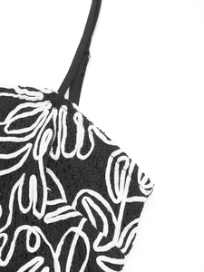 Détail de la robe sans manches noire avec broderie feuille blanche et boucle en métal
