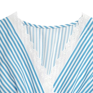 Macro detail of the V-neck with white lace embroidery on blue striped dress